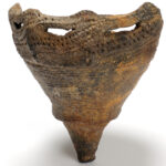 【縄文時代の青森②】土器が語る縄文人の暮らし…文様から見える交流の始まり Ancient ceramic vessel with a wide perforated rim and tapered body in brown, textured surface.