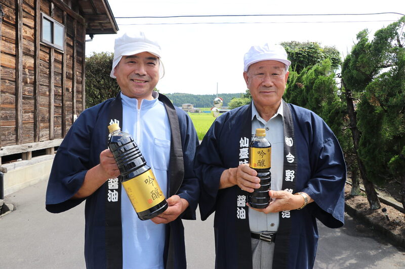 Konno Brewing's factory manager, Masanobu Goto (left), and representative director, Akio Konno (right), holding bottles of "Ginjo" sake